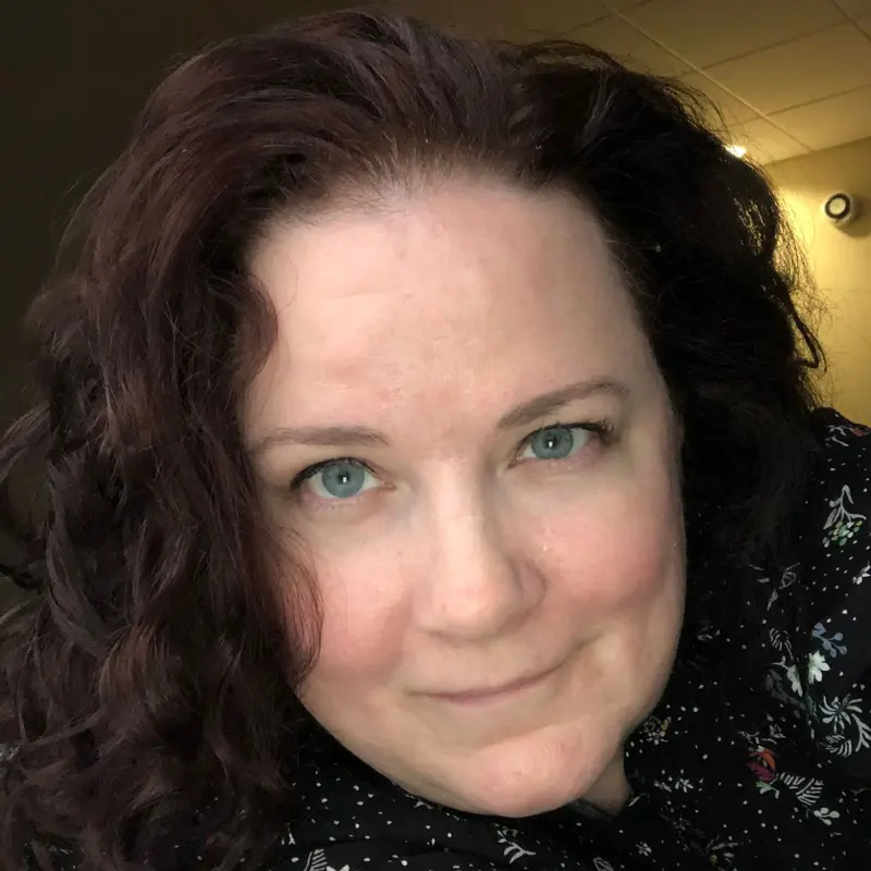 Jennifer J. Williams, smiling, with long dark curly hair